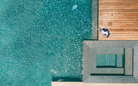 Man with net cleaning pool.